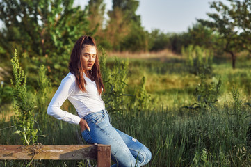 Outdoor portrait of a young girl in the countryside . The model is dressed in jeans and a white shirt