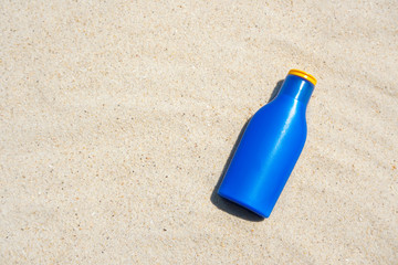 blue sun block bottle on the beach sand