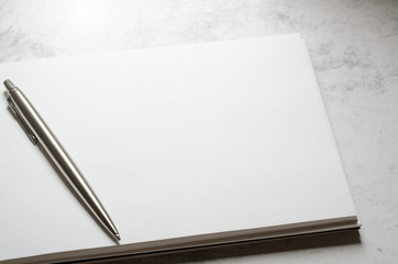 Notepad with metal gray pen on a stone background. Concept elegant business style. Copy space