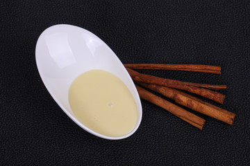 Condenced milk in the bowl with sinnamon and pastry