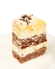 A piece of sweet fresh cake with yellow and chocolate cream on a plate on a white background