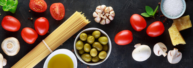Food ingredients for italian pasta, spaghetti on black stone slate background. Banner.
