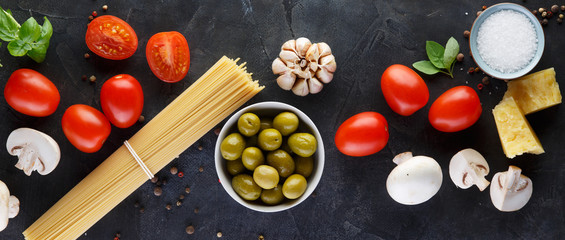 Food ingredients for italian pasta, spaghetti on black stone slate background. Banner.
