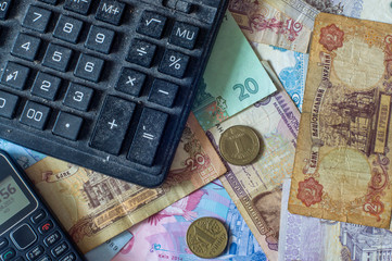 Money. Ukrainian hryvnia, various coins. Dusty calculator and old mobile phone. Old and new bills. Cash.