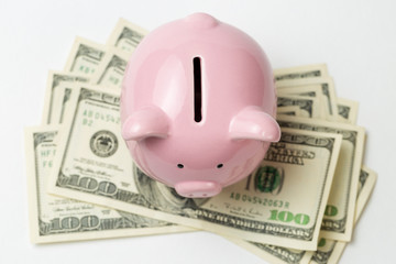 Pig piggy bank on the background of 100 US dollar bills and physical coins of bitcoins. Concept of wealth and exchange.	