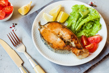 Steak baked salmon fish on a plate with fresh vegetables.