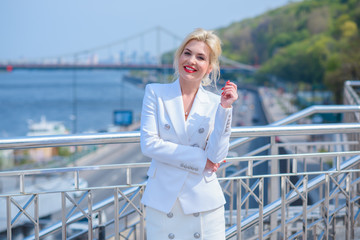 Fototapeta premium Luxurious woman in white suit at city. White dress code for lady. Fashionable business clothes 
