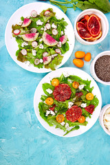Mix salads on blue background. Fresh Citrus Salad with arugula feta, chia, kumquat and blood orange.  Watermelon Radish salad. Vegan, vegetarian, clean eating, dieting, food concept.