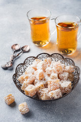 Turkish delight with hazelnut in carved metal bowl and tea in glass Cup, selective focus