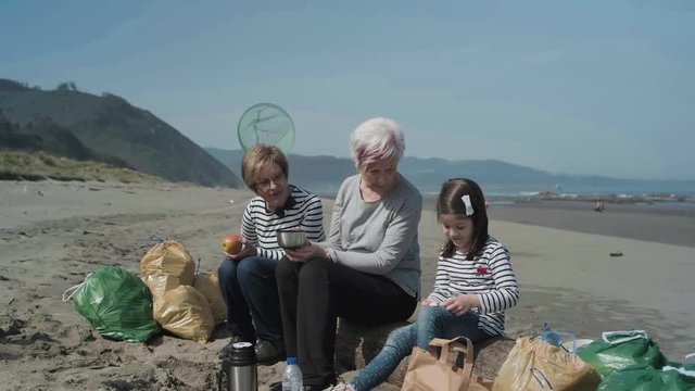 Group of volunteers resting and eating after cleaning the beach