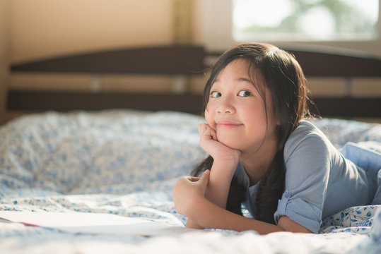 Asian girl reading book on the bed