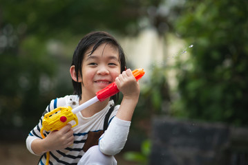 Cute Asian child playing with water gun in the summer