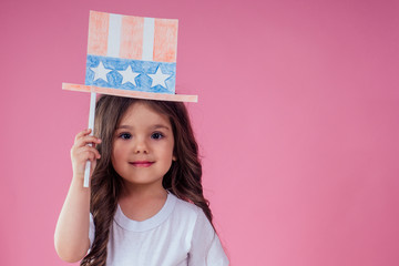 little girl with usa flag paper crown and torch freedom studio pink background