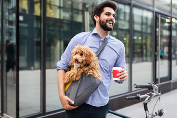 Handsome business man on street drinking coffee with dog