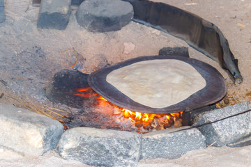 Traditional arabic pita bread cooking on fire in bedouin dwelling