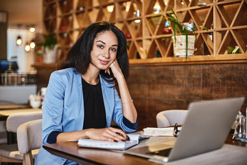 Fototapeta premium Continue to seek new goals. Young beautiful businesswoman smiling, writing in notebook while working in cafe