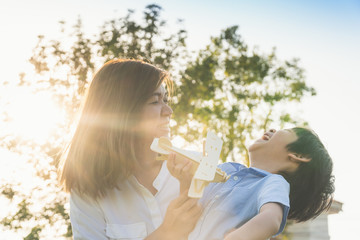 Obraz premium Cute Asian mother and son playing wod airplane together in the park outdoors
