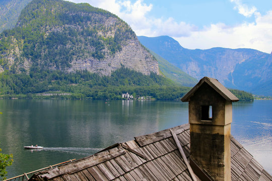 A beautiful view of the hallstatt lake, in the foreground an old wooden roof with smokestack