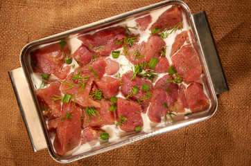 Marinated in milk and green meat in stainless steel utensils on fabric