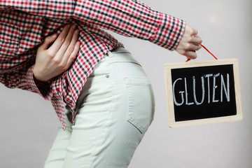 Woman feeling stomach cramps holding gluten board