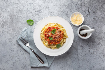 penne pasta with Bolognese sause in white plate, top view