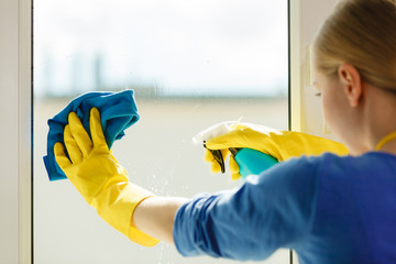 Girl cleaning window at home using detergent rag