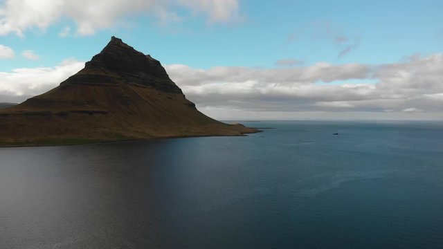 Aerial recoding of mount Kirkjufell, Iceland pushing towards the mountan with the endless open ocean in the background.