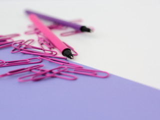 Closeup of purple stationery. Pens and paperclips on white and purple backgrund.