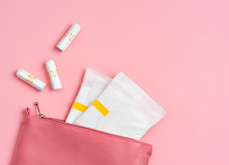 Sanitary pads and tampons in cosmetic bag on pink background. Concept of critical days, menstruation