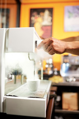 Close-up of man controlling the process of making coffee drink on coffee machine at the restaurant