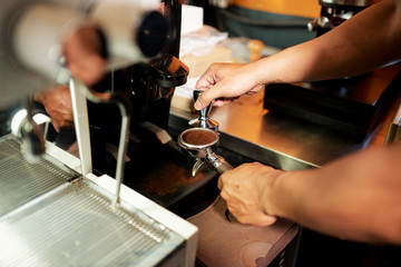 Close-up of male barista grinding coffee in powder with special equipment to prepare fresh coffee drink