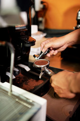 Fototapeta na wymiar Close-up of bartender making powder from roasted coffee beans for coffee machine in cafe