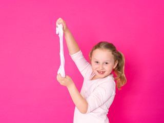 girl is playing with yellow slime in front of pink background