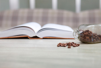 An open book on a white table and a bottle of coffee grains, the concept of education