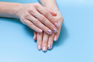 Beautiful female hands and a fashionable manicure on a blue background
