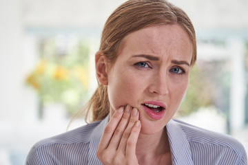 Portrait Of Young Woman Suffering With Toothache Touching Jaw