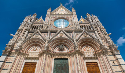 Fototapeta na wymiar Siena, Tuscany / Italy: Siena Cathedral seen from Via del Capitano with tourists strolling there