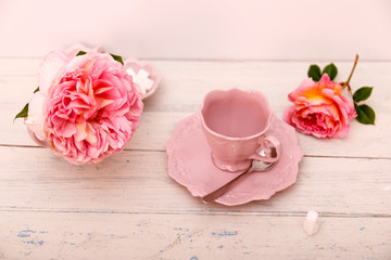 Big roses and coffee on a white wooden background.
