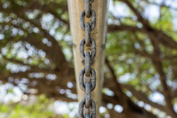 rust chain hanging on pipe on unfocused blurred park outdoor background 