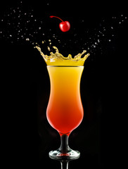 cherry falling into a splashing tequila sunrise isolated on black