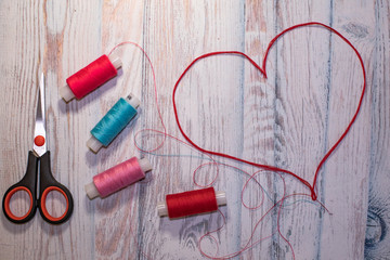 Hobbies and crafts concept, heart of factory threads on blue background, sewing thread and scissors background for text