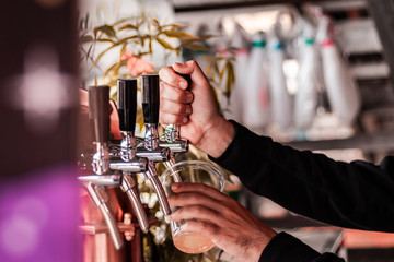 Artisan beer company serving free drinks during music festival. Macro shot of hands and levers.  - obrazy, fototapety, plakaty