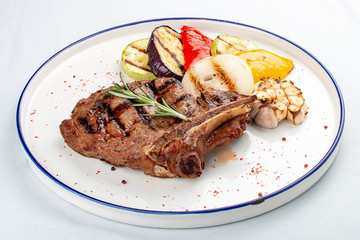 Veal bone steak with grilled vegetables on a white background