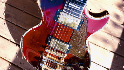 electric guitar behind the glass with water drops . closeup