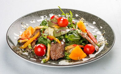 Warm salad with vegetables, arugula and veal