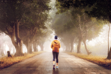 Woman traveler walks along a foggy forest road