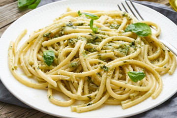 Pesto spaghetti pasta with basil, garlic, pine nuts, olive oil. Rustic table, close up