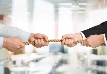 Business people pulling rope in opposite directions at office