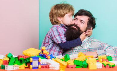 Happy family. Father and son have fun with bricks. Child development and upbringing. Bearded hipster and boy play together. Happy childhood. Dad and child build of plastic blocks. Child care concept