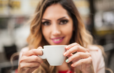 Portrait of woman sitting in outdoor cafe and drinking coffee